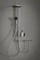 Duschanlage an grauer Wand mit Kopf- und Handbrause, Thermostat und Ablage für Pflegeprodukte. Ideal Standard Design mit klarer Linienführung und funktionalem Aufbau.